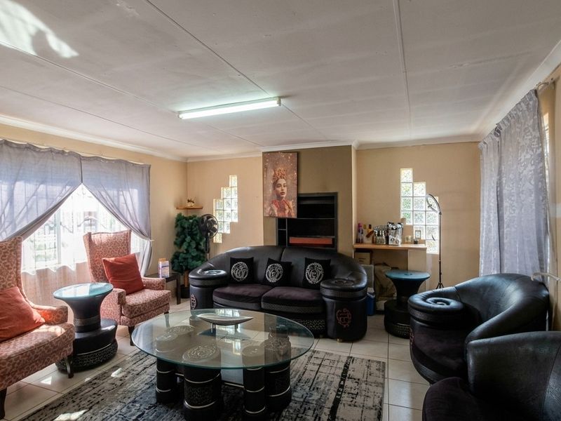 A spacious living room featuring tiled flooring, built-in fireplace, and decorative glass block windows, offering a functional layout for comfortable family living.