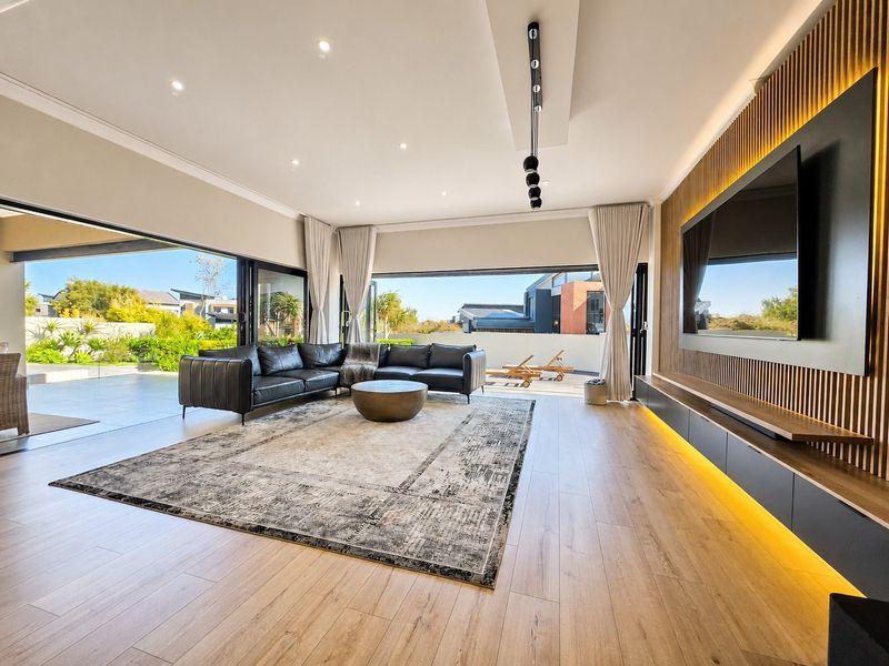 Modern open-plan living area featuring timber slat wall paneling, integrated media console with LED lighting, and expansive sliding doors opening to a patio.
