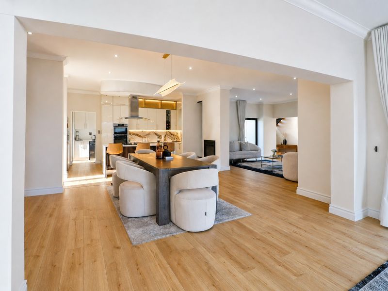 Spacious open-plan living and dining area featuring modern kitchen cabinetry, integrated appliances, fireplace, and high-quality laminate flooring throughout.