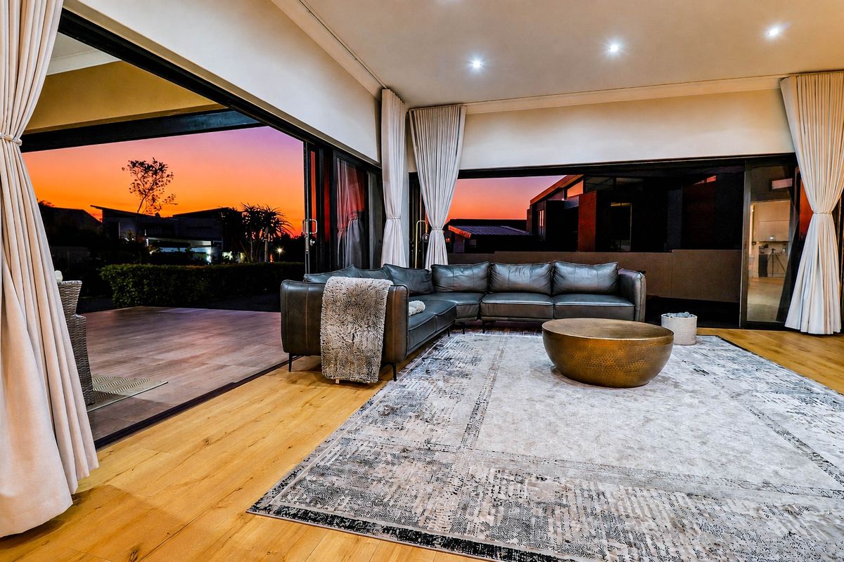 Spacious living room featuring hardwood flooring, recessed lighting, and expansive sliding glass doors that open to an outdoor patio area.