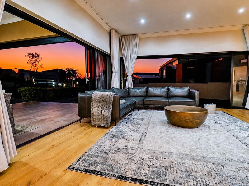 Spacious living room featuring hardwood flooring, recessed lighting, and expansive sliding glass doors that open to an outdoor patio area.