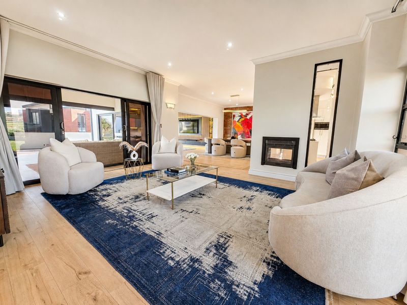 Spacious open-plan living area featuring hardwood flooring, a modern built-in fireplace, and large sliding glass doors leading to an outdoor patio.