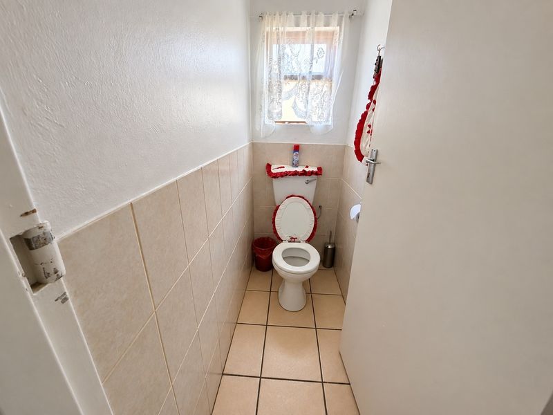 A compact guest bathroom featuring neutral ceramic wall and floor tiles.