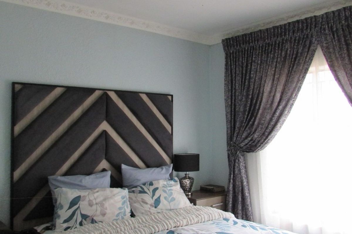 A cozy bedroom featuring decorative ceiling cornicing and a central flush mount light fixture, providing a comfortable and well-maintained sleeping space.