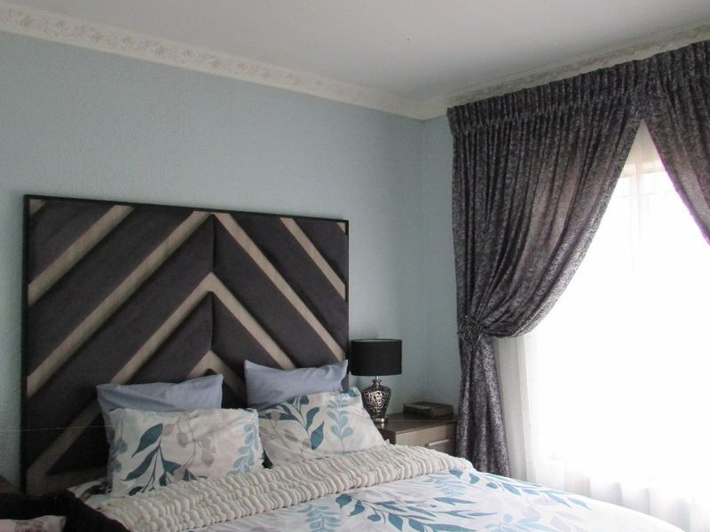 A cozy bedroom featuring decorative ceiling cornicing and a central flush mount light fixture, providing a comfortable and well-maintained sleeping space.