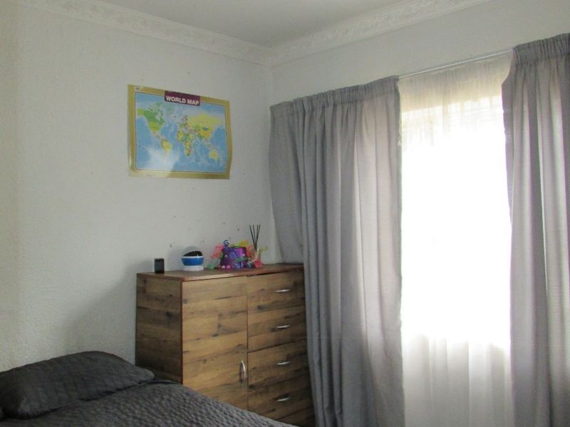 A standard bedroom featuring decorative ceiling cornicing and a central light fixture, providing a functional space with natural light.