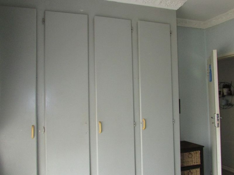 Bedroom featuring built-in cupboards with decorative cornice detailing.