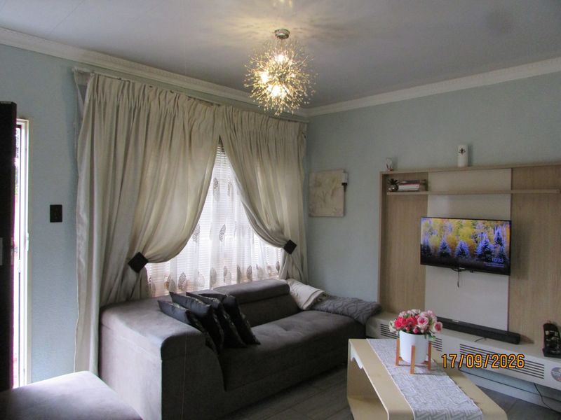 A cozy living room featuring a built-in media unit, decorative coving, and tiled flooring, providing a functional and well-maintained space.