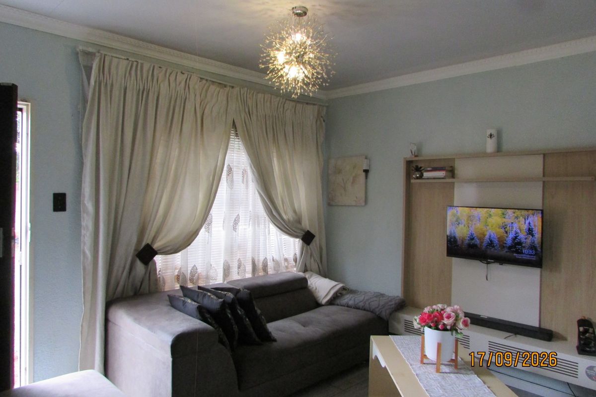 A cozy living room featuring a built-in media unit, decorative coving, and tiled flooring, providing a functional and well-maintained space.