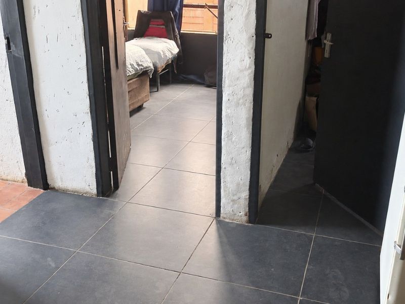 A tiled hallway area connecting multiple rooms, featuring dark floor tiles and contrasting door frames.