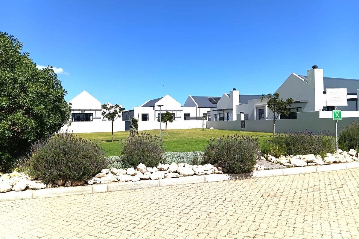 A well-maintained residential complex featuring white facades, chimneys, and a shared landscaped garden area with paved driveway access.