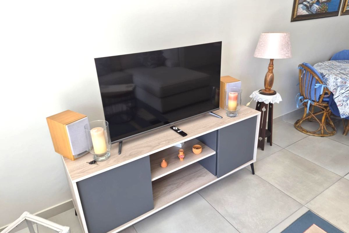 A living room area featuring neutral tiled flooring and a modern media console unit.
