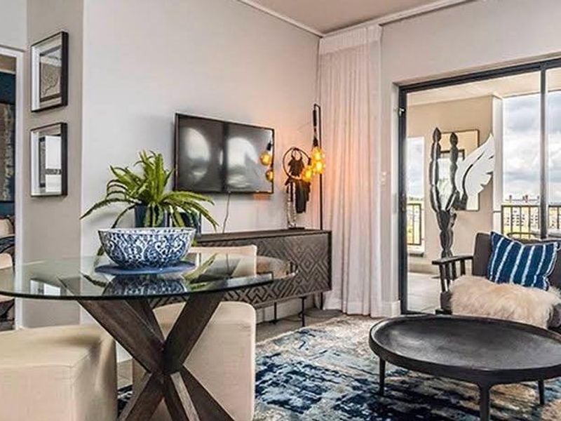 Modern open-plan living area featuring a seamless transition to a private balcony through large sliding glass doors, with integrated laundry and kitchen cabinetry.