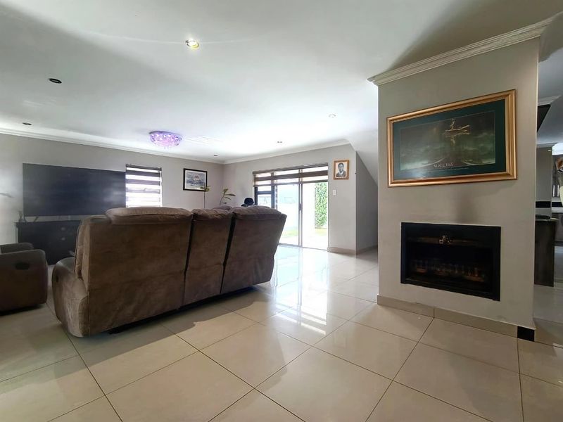Spacious living room featuring large format floor tiles, a built-in fireplace, and sliding glass doors providing access to the outdoor area.