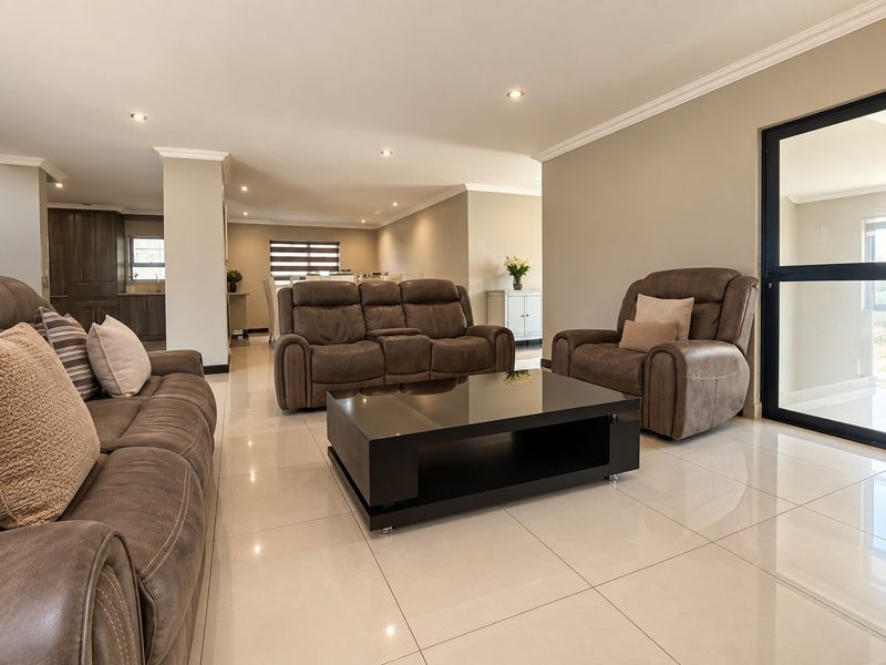 Spacious open-plan living area featuring polished porcelain tiles, recessed lighting, and seamless flow into the adjacent kitchen space.