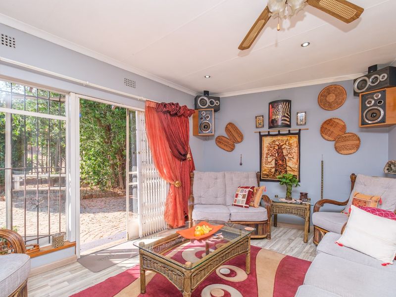 A comfortable living room featuring laminate flooring, recessed lighting, a ceiling fan, and a sliding glass door providing direct access to the garden.