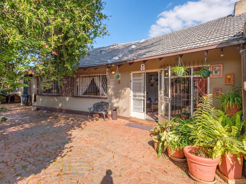 A rear exterior view of the house featuring a paved patio area, tiled roof, and security-fitted windows and doors.