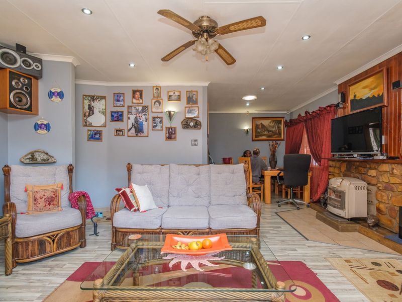 Open plan living and dining area featuring a stone fireplace, wood paneling, ceiling fan, and recessed lighting.