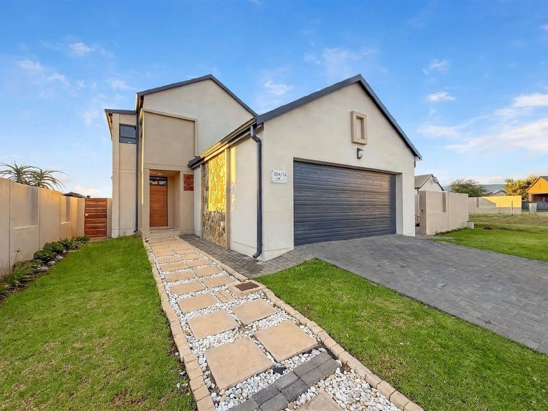 Modern front elevation featuring a double garage, stone-clad accents, and a well-maintained paved walkway leading to the main entrance.