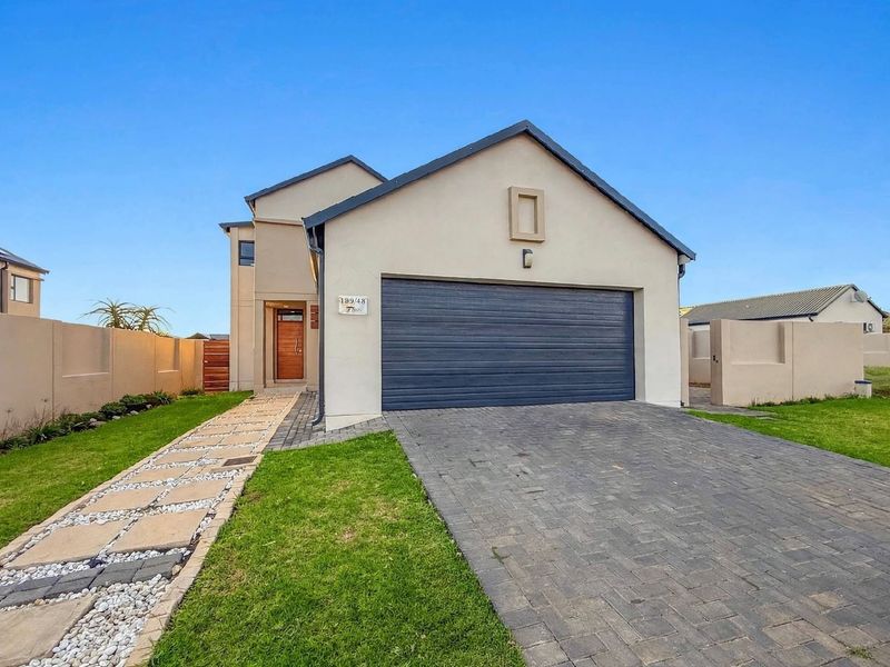 Modern double-storey residential home featuring a paved driveway, double garage, and a landscaped front garden with a stone walkway.