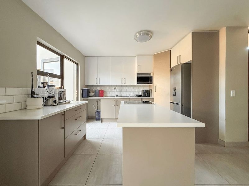 Modern kitchen featuring a central island, stone countertops, subway tile backsplash, and ample built-in cabinetry with integrated appliances.