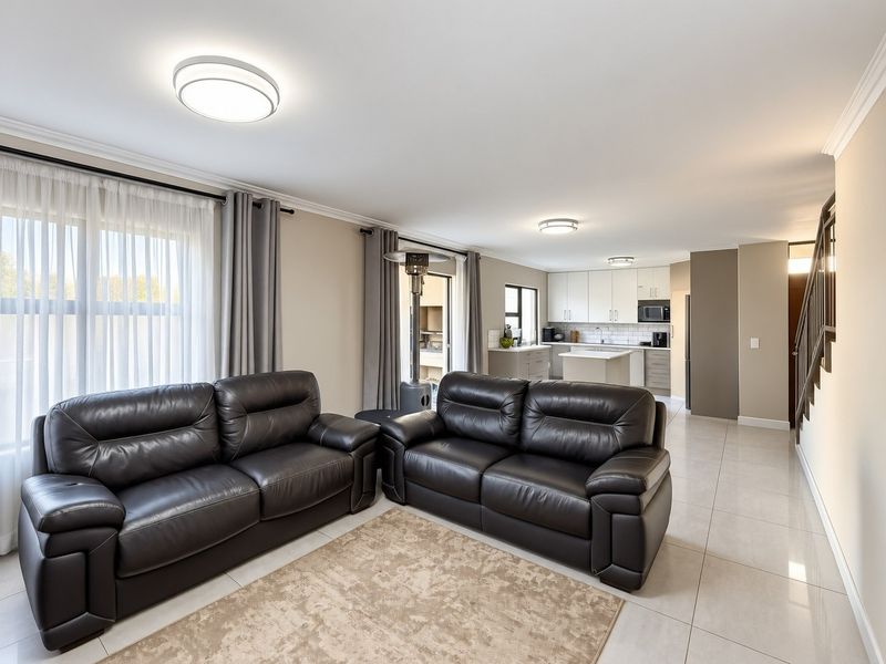 Spacious open-plan living area featuring tiled floors, modern kitchen cabinetry with an island, and direct access to an outdoor patio area.