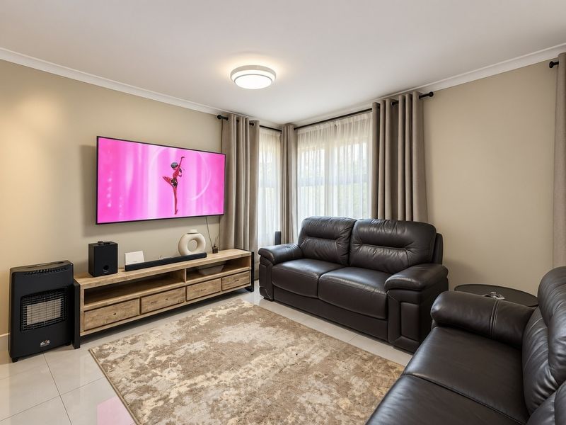 A well-maintained living room featuring neutral wall tones, tiled flooring, and large windows with fitted curtain rods.