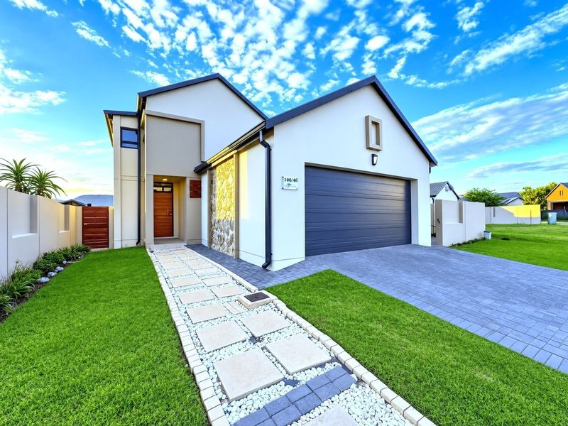 Modern front elevation featuring a double garage, stone cladding accents, a paved driveway, and a landscaped walkway leading to the main entrance.