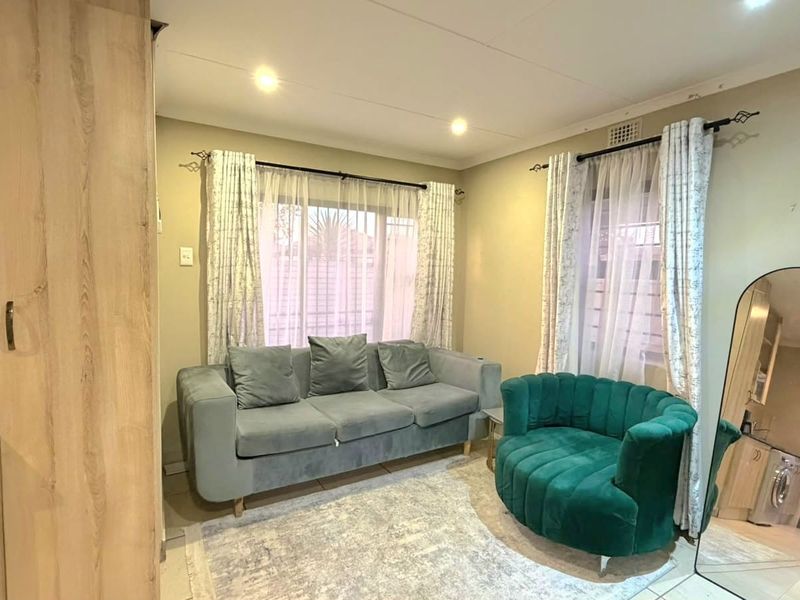 Open plan living area featuring tiled flooring, recessed downlights, and integrated cabinetry, providing a functional and compact living space.