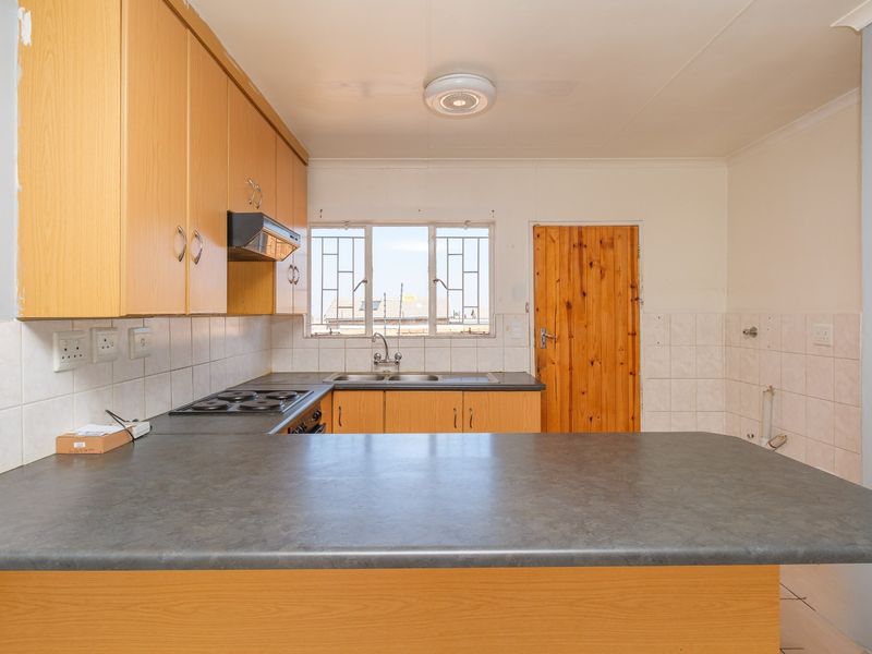 Functional kitchen featuring laminate cabinetry, built-in electric hob, extractor fan, and a double bowl sink with tiled splashbacks.
