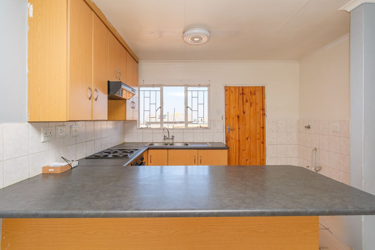 Functional kitchen featuring laminate cabinetry, built-in electric hob, extractor fan, and a double bowl sink with tiled splashbacks.