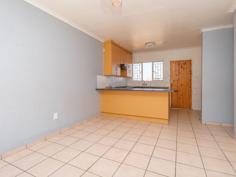 Open plan kitchen area featuring built-in cabinetry, tiled flooring, and direct access to an exterior door.