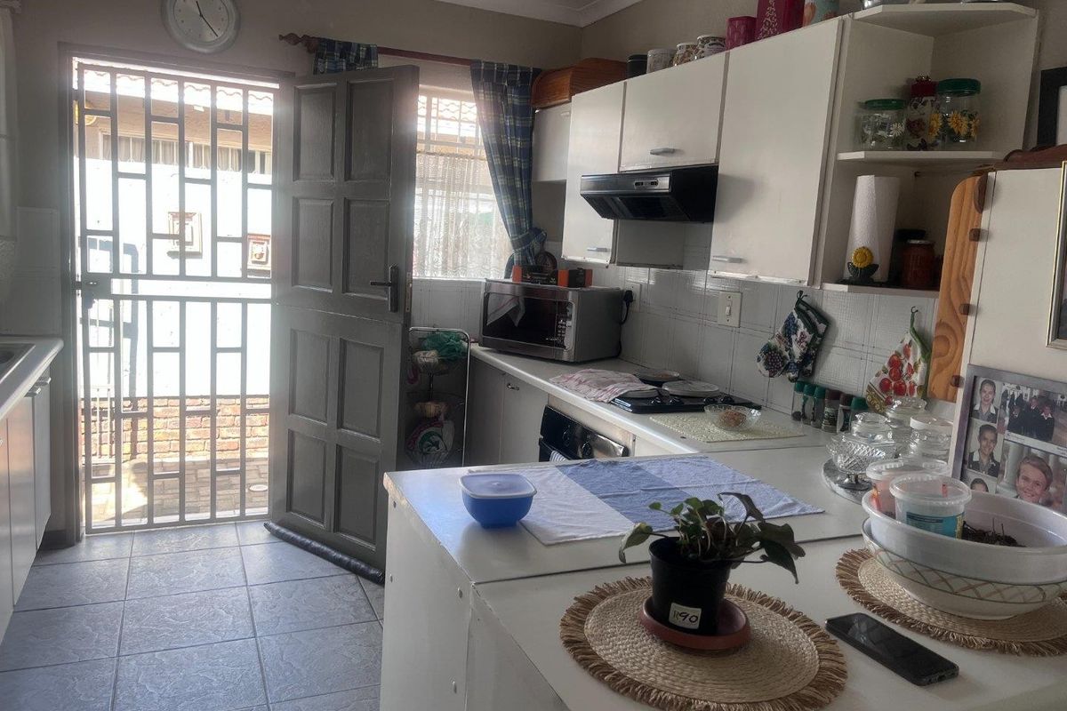 A functional kitchen featuring built-in cabinetry, a hob, and an extractor fan, with direct access to an exterior area through a security gate.