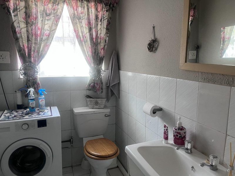 A functional bathroom featuring a toilet, washbasin, and tiled wall finishes, providing essential utility space within the townhouse.