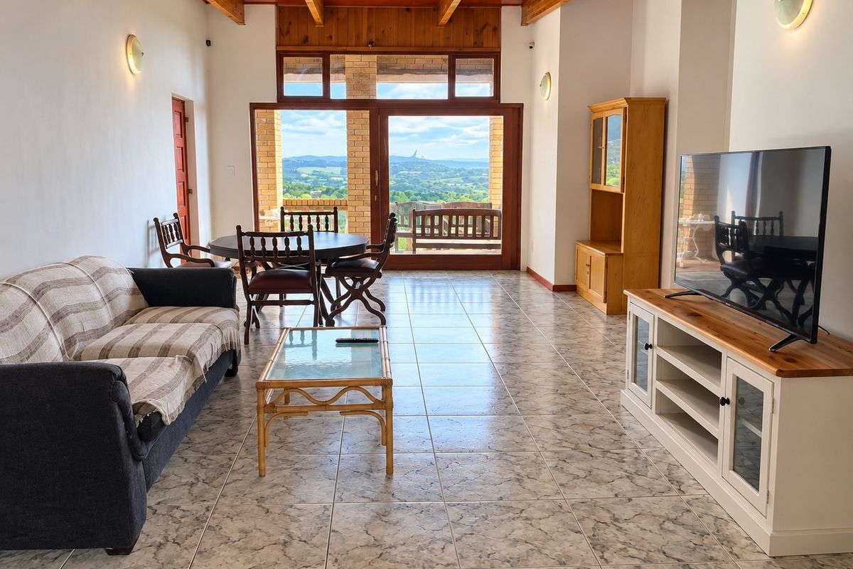 Spacious open-plan living and dining area featuring exposed timber ceiling beams, tiled flooring, and large sliding doors offering scenic landscape views.