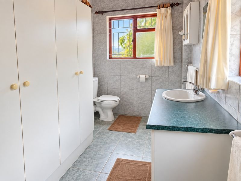 A functional bathroom featuring built-in storage cupboards, a vanity basin, and tiled surfaces throughout, offering a clean and practical layout.