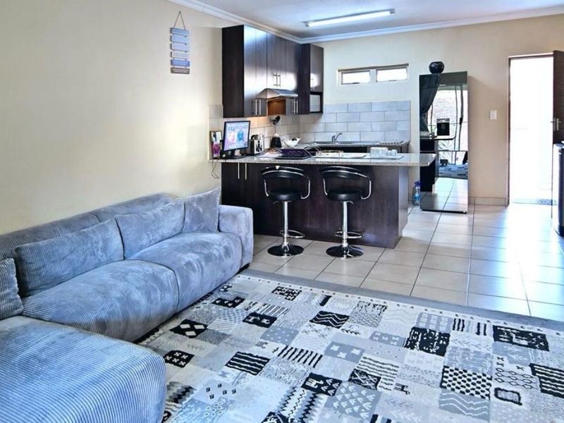 Open-plan living area featuring a kitchen with dark wood cabinetry, granite breakfast bar, and tiled flooring throughout.