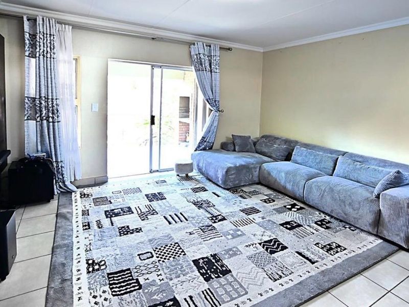 A living room featuring tiled flooring and a sliding glass door providing access to the outdoor area.