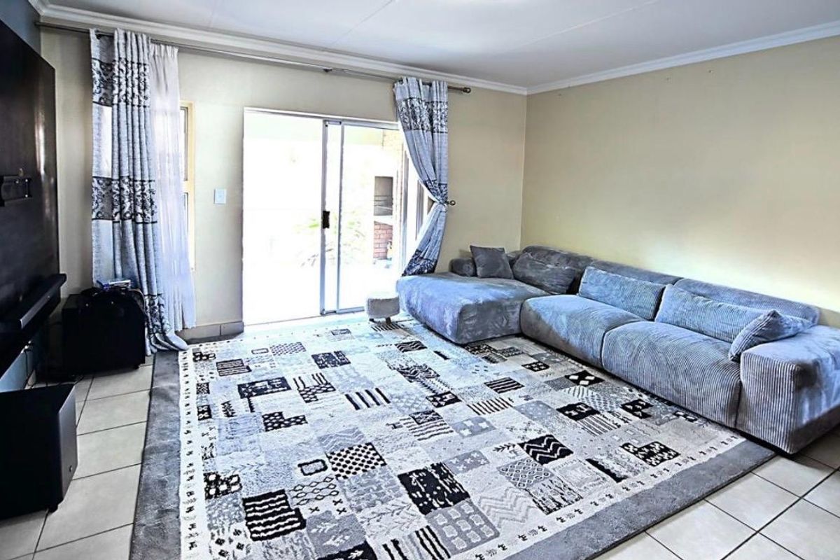 A living room featuring tiled flooring and a sliding glass door providing access to the outdoor area.