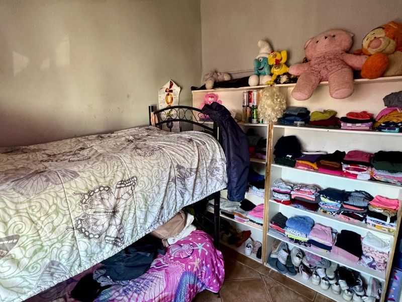 A bedroom featuring tiled flooring and built-in shelving, currently showing significant signs of ceiling water damage and wear.