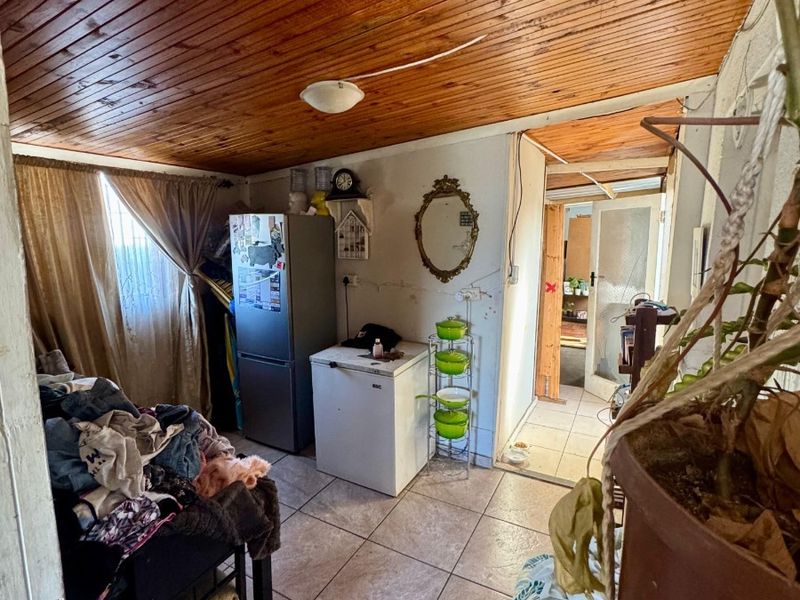 A utility or scullery area featuring tiled flooring and a timber-clad ceiling, requiring cosmetic updates and repairs to wall finishes.