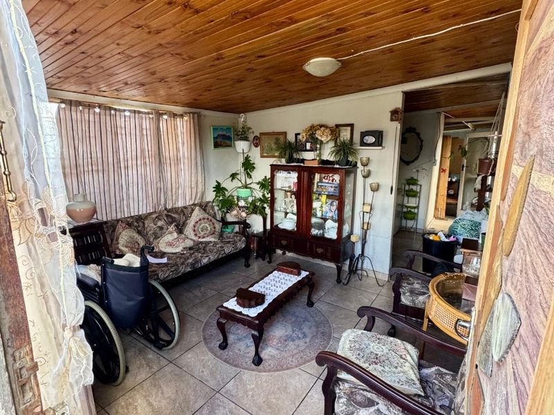 A living area featuring a timber tongue and groove ceiling and ceramic tiled flooring, providing a dated but functional space.