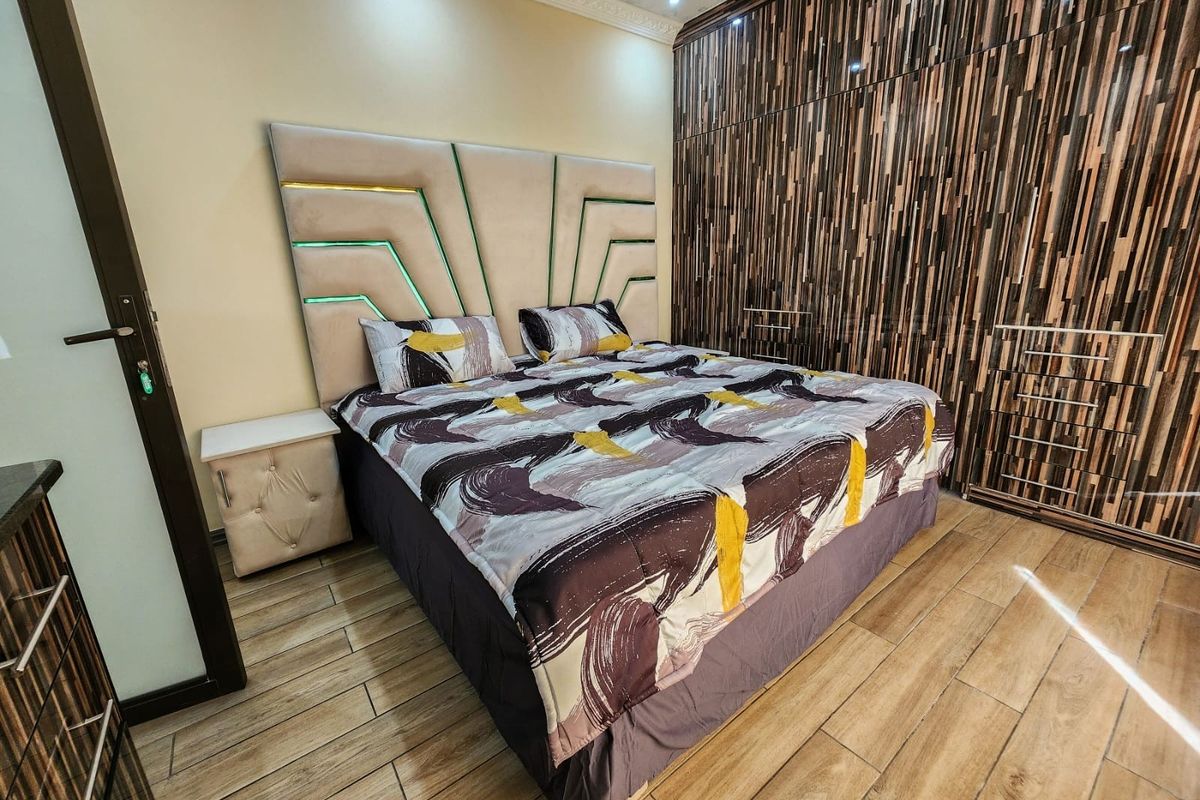 A well-maintained bedroom featuring extensive built-in wooden cabinetry and modern laminate flooring, providing ample storage and a clean aesthetic.