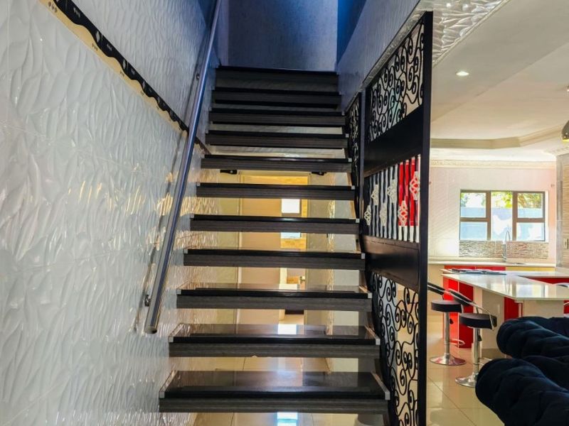 A modern staircase featuring dark treads, a sleek metal handrail, and a decorative metal privacy screen, leading to the upper level of the townhouse.