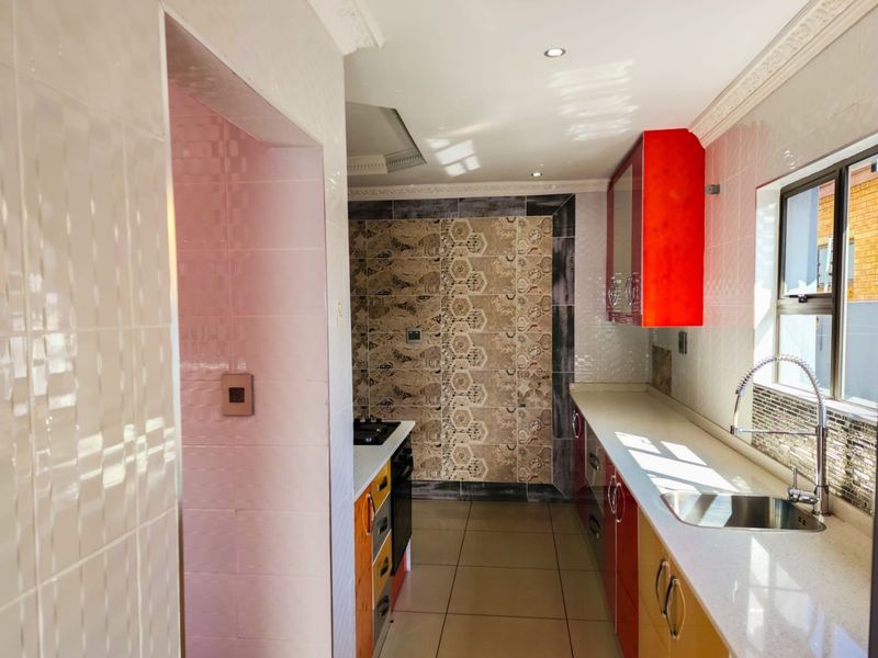 A functional kitchen featuring vibrant cabinetry, stone countertops, a stainless steel sink with a gooseneck faucet, and decorative tiled splashbacks.