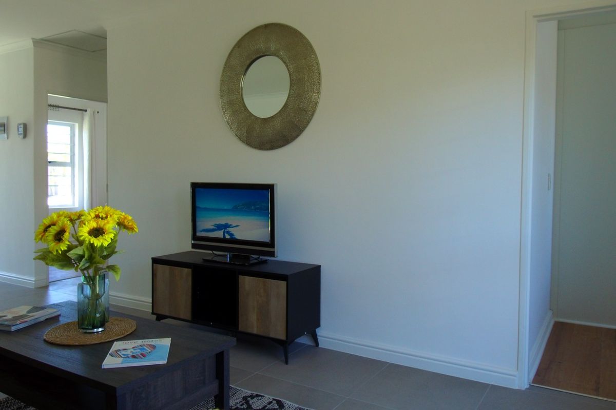 A bright and neutral living area featuring clean tiled flooring and crisp white walls, providing a versatile space for relaxation.