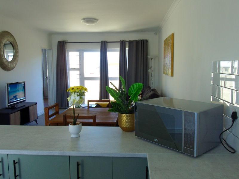An open-plan living and dining area featuring a kitchen peninsula with subway tile backsplash, laminate countertops, and access to a sliding glass door.