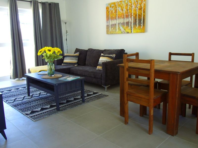 An open-plan living and dining area featuring neutral tiled flooring and a large sliding glass door providing natural light.