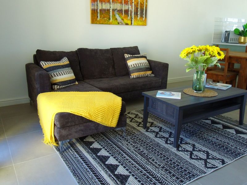 An open-plan living and dining area featuring neutral tiled flooring and a modern kitchen with a subway tile backsplash.
