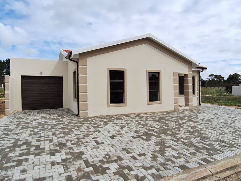 A modern single-story house featuring a paved driveway, single garage, and clean exterior finishes in a quiet residential setting.